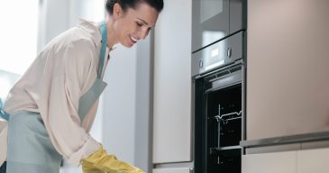 Young dark-haired woman cleaning kitchen appliances Kitchen work. Young dark-haired woman cleaning kitchen appliances